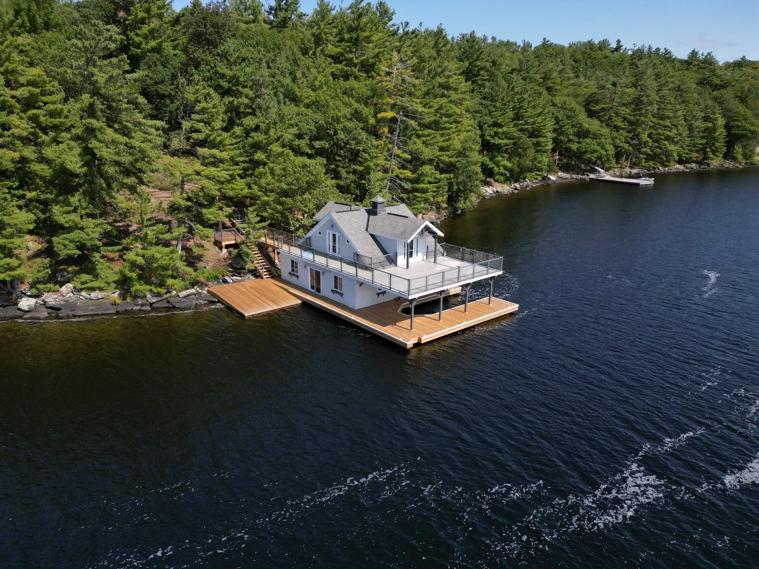 Aerial view of a Muskoka boathouse and cedar dock on a forested shoreline