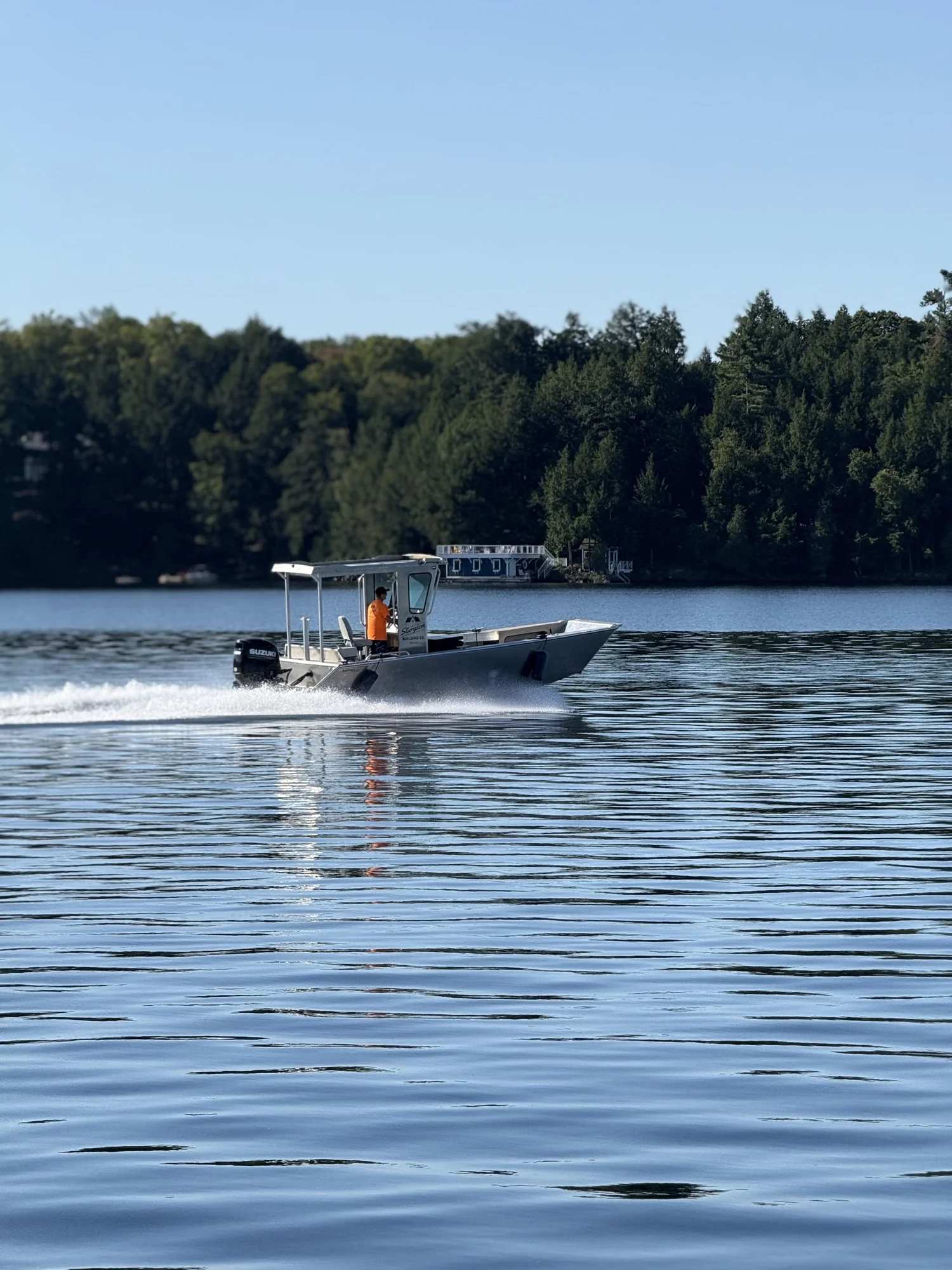 Boat crossing the lake near a wooded shoreline